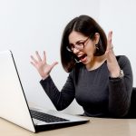 Young beautiful stressed businesswoman screaming at laptop
